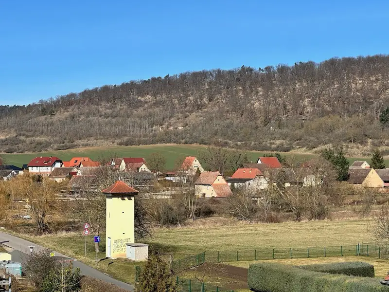 Dorfansicht mit roten Dächern und Hügeln