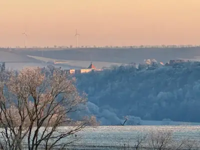 Winterlandschaft mit Burg und Windrädern am Horizont