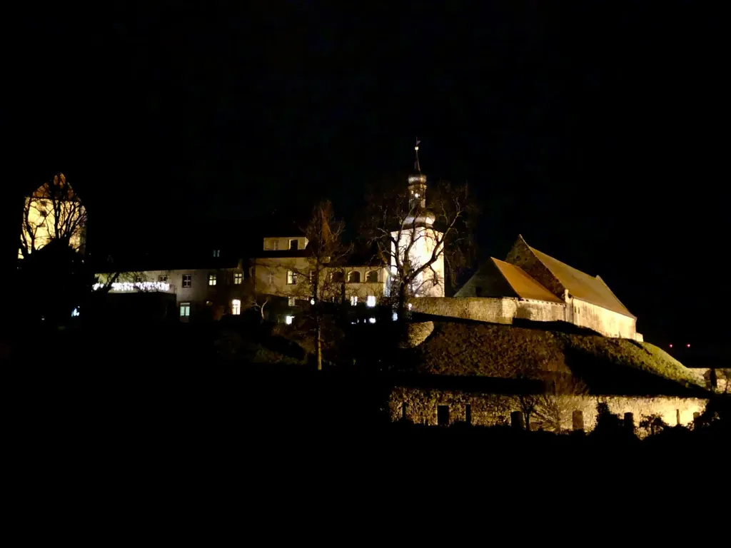 Beleuchtete Burg bei Nacht mit Kirchturm