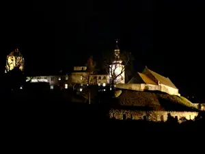 Beleuchtete Burg bei Nacht mit Kirchturm