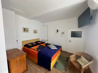 Unstruttal bedroom with double bed and rattan armchair