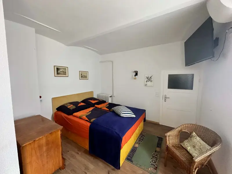 Unstruttal bedroom with double bed and rattan armchair